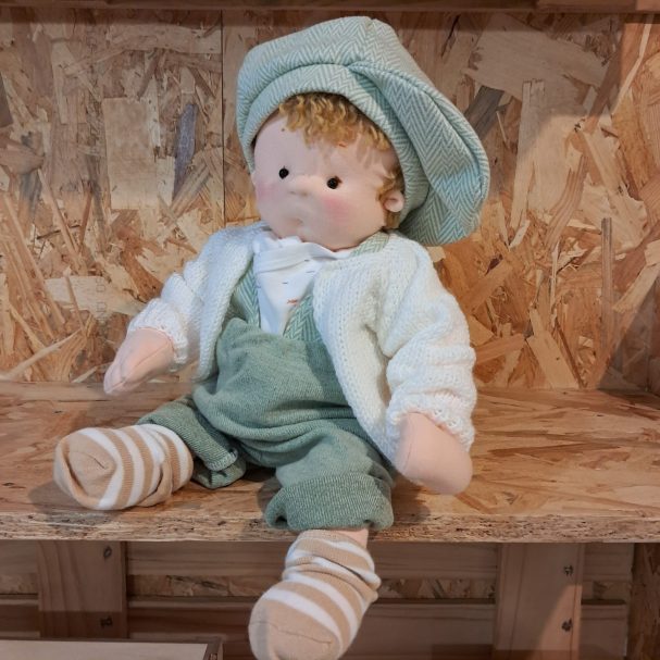 Muñeca de tela de pelo rubio rizado con boina verde, peto verde y chaqueta blanca de punto