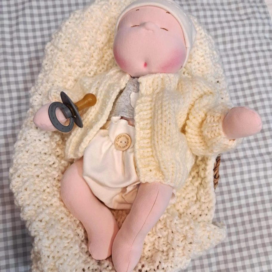 muñeco bebé unico personalizado regalo baby doll Muñeca de trapo con chupete, vestida con un suéter amarillo y envuelta en una manta.